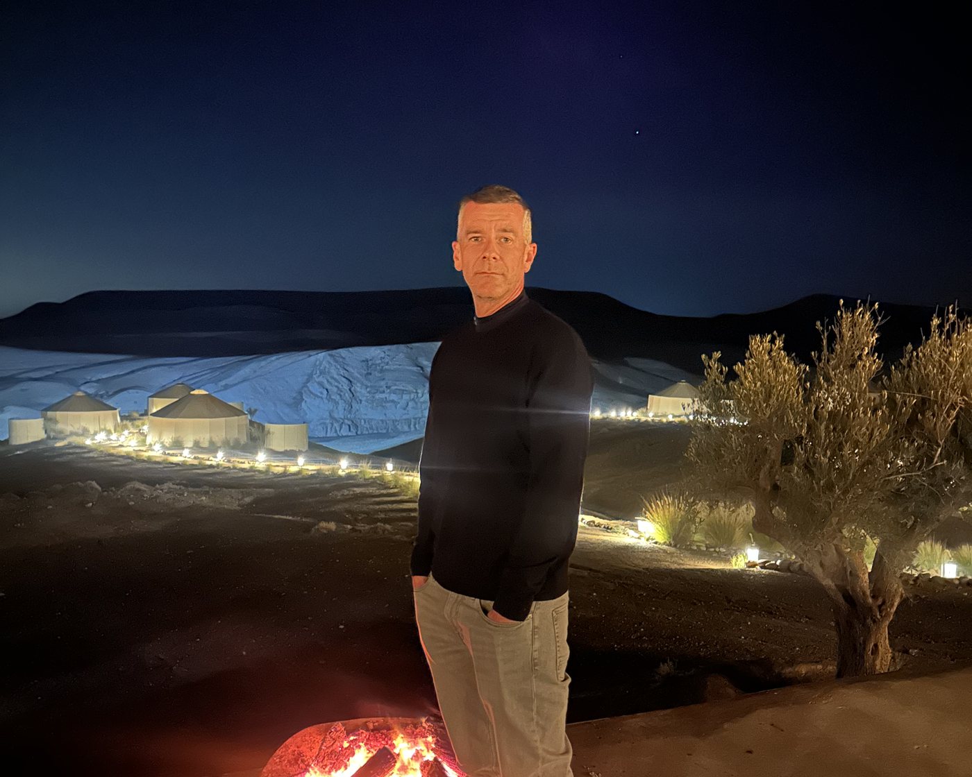 Carsten Diederich am Abend über einem beleuchteten Camp in der Wüste