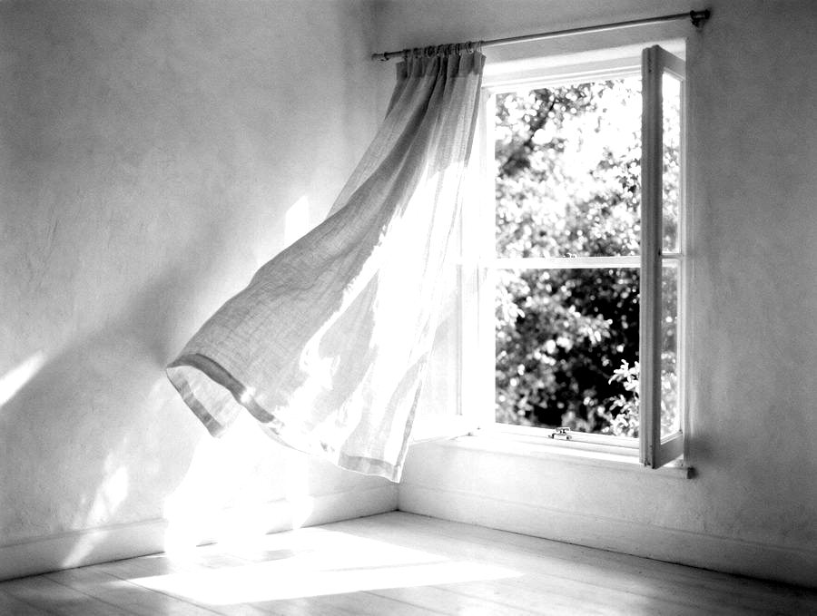 Offenes Fenster mit einem Vorhang im Luftzug